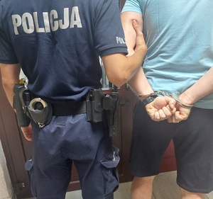 policjant z zatrzymanym mężczyzną skutym w kajdanki