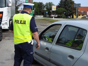 policjant stojący przy samochodzie osobowym w którym siedzi kierowca