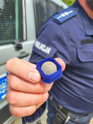 policjant trzyma w ręce odznakę honorowego dawcy krwi