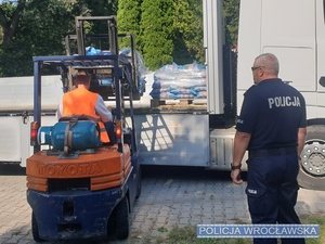 Policjanci układają worki na cmentarzu