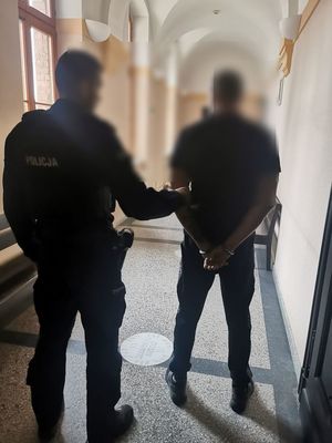 Policjant z zatrzymanym mężczyzną w budynku