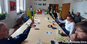 Policjanci w pomieszczeniu wraz z mieszkańcami domu opieki trzymają w rękach odblaski