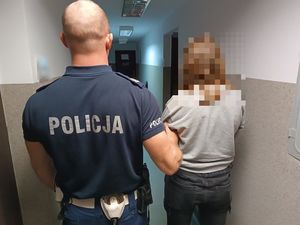 Policjant prowadzi zatrzymaną kobietę