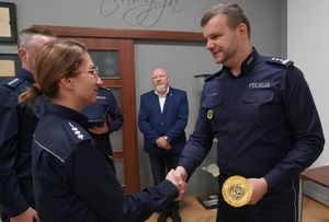 Inspektor Norbert Kurenda gratuluje podając rękę i przekazuje puchar policjantce