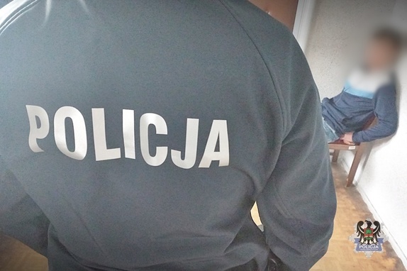 policjant stojący obok zatryzmanego siedzącego na krześle