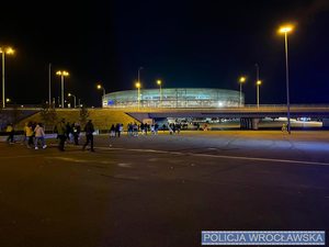 Wieczorowa pora, ludzie idą na oświetlony stadion