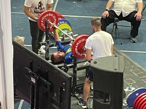 mężczyzna wyciska sztangę podczas zawodów