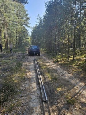 w lesie samochód osobowy ciągnący tor kolejowy