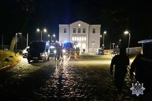 Wozy strażackie i policyjne wraz z policjantami i strażakami przed budynkiem