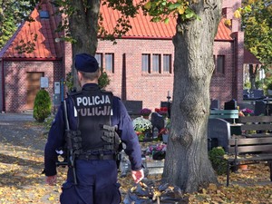 policjant idący alejką cmentarną