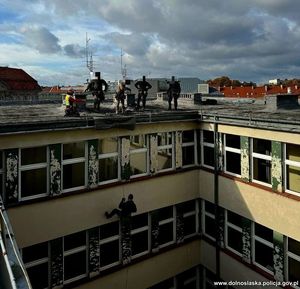 policjanci spuszczający się na linie z dachu budynku