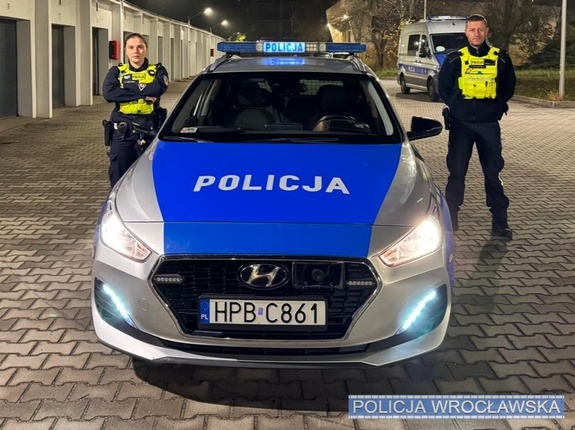 policjant i policjantka przy radiowozie