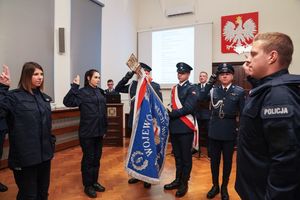 poczet sztandarowy i opuszczony sztandar podczas ślubowania po bokach policjanci ślubujący na sztandar