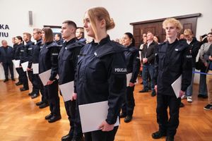 nowo przyjęci policjanci z dyplomami w rękach stoją w dwuszeregu