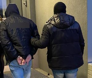 policjant po cywilu prowadzi zatryzmanego skutego w kajdanki