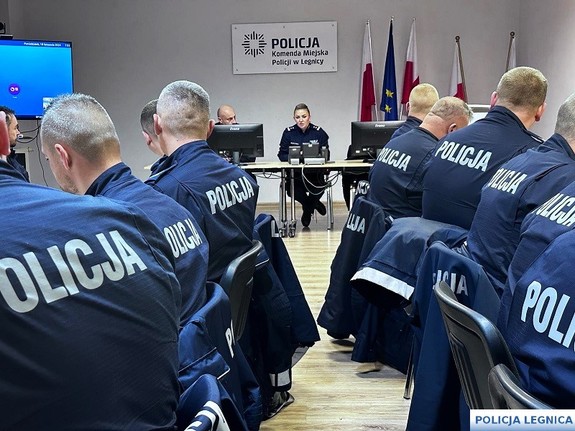 policjanci siedzący na wykąłdach w mundurach na sali