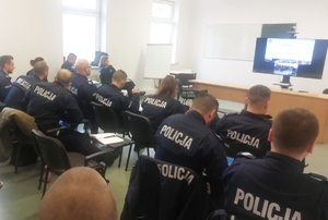 policjanci siedzący na wykąłdach w mundurach na sali