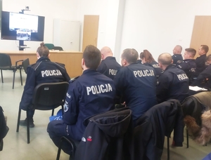 policjanci siedzący na wykąłdach w mundurach na sali