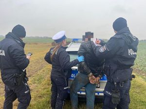 policjanci z zatrzymanym mężczyzną przy radiowozie