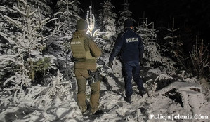 policjant i leśnik przeszukują las w śniegu