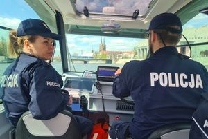 policjantka i policjant płyną motorówką policyjną