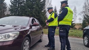 dwaj policjanci kontrolują pojazd osobowy