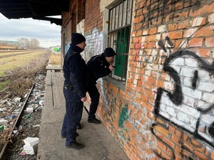 dwaj policjanci zaglądają do okien pustostanu