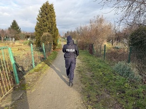 policjantka idzie ścieżką na ogródkach działkowych