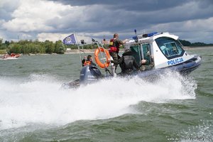 policjanci płynący motorówką policyjną po rzece