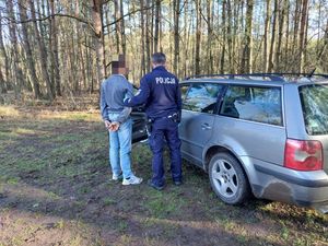 Policjant z zatrzymanym mężczyzną przy samochodzie