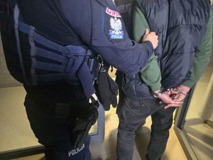 policjant prowadzi zatrzymanego skutego w kajdanki