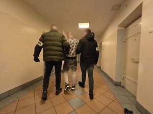 dwóch policjantów prowadzi zatrzymanego