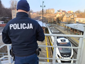 Policjant na wiadukcie obserwuje jadący z peronu pociąg