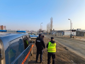 policjant i strażnik ochrony kolei obserwują teren kolei