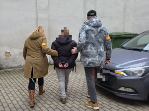 Policjanci w cywilu prowadzą zatrzymaną kobietę