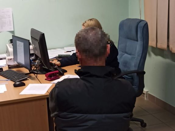 Policjant przesłuchuje zatrzymanego siedzącego na krześle
