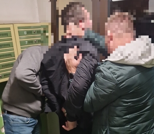 policjanci prowadzą mężczyznę skutego w kajdanki - widok z przodu