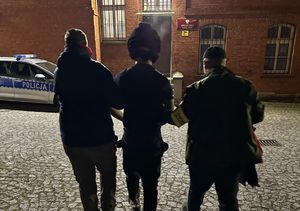 dwóch policjantów prowadzi zatrzymanego