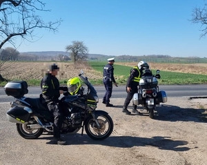 policjanci na motorach kontrolują zatrzymanego motocykliste