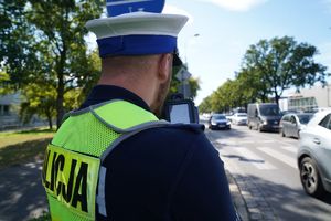 policjant mierzy prędkość nadjeżdżającemu pojazdowi  ręcznym miernikiem prędkości