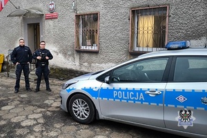 policjanci w mundurach stojacy koło radiowozu