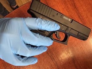 pistolet w rece z niebieską rekawiczką