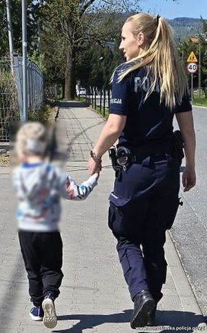 policjantka prowadzi dziecko za rękę