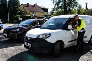dwaj policjanci kontrolują samochody osobowe