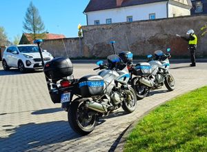 dwa motory policyjne w tle policjant zatrzymujący samochód osobowy