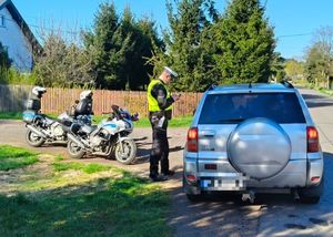 policjant kontroluje kierowcę samochodu osobowego z boku dwa motocykle