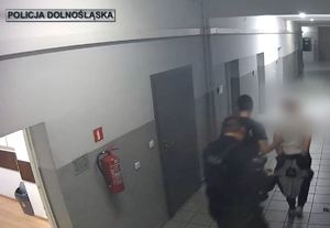 Policjanci prowadzą zatrzymanego korytarzami komendy
