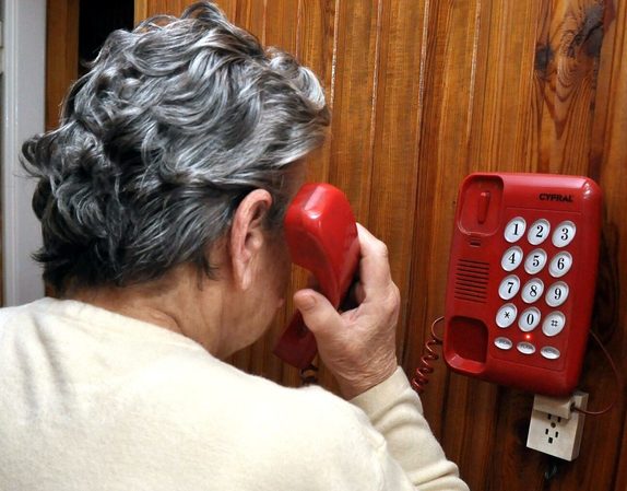 starsza kobieta obiera stacjonarny telefon