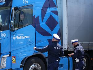 dwaj policjanci kontrolują kierowcę tira siedzącego w samochodzie