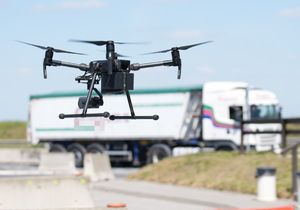 dron powoli wznosi się w tle jadące samochody ciężarowe